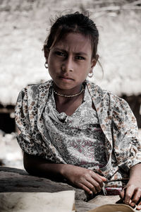 Portrait of young woman looking away while sitting outdoors