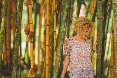 Young woman standing against bamboos