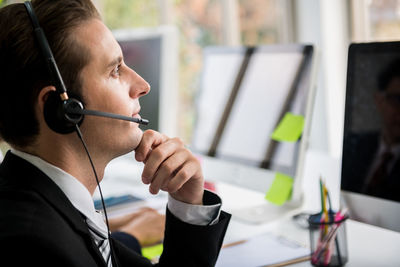 Side view of thoughtful customer service representative looking away in office