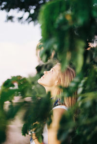 Side view of woman looking away against trees