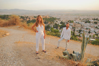 Portrait of young couple standing on cobbled road during sunset