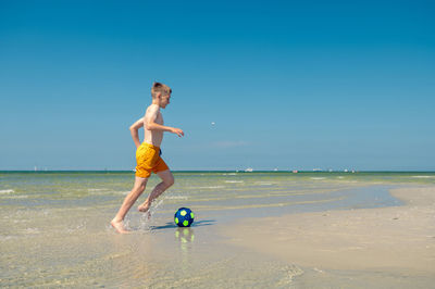 Full length of man on beach against clear sky