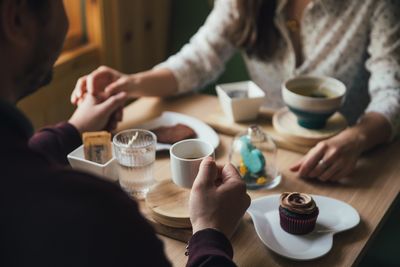 Midsection of woman having coffee at table