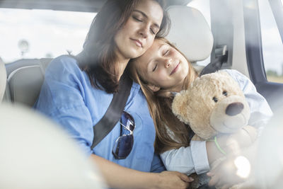 Mother and daughter on road trip sitting in car, sleeping