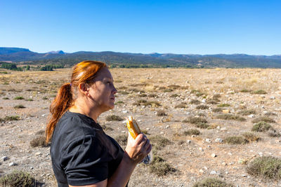 Side view of man standing on landscape against clear sky