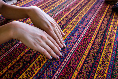 High angle view of woman hand on multi colored carpet