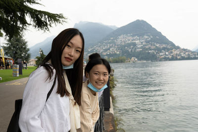 Portrait of smiling woman standing by water at mountain