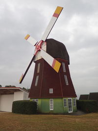 Traditional windmill on building against sky