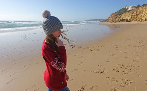 Girl in a bobble hat on the beach in portugal in winter