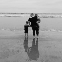 Rear view of father and daughter walking on beach