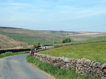 Road amidst field against sky