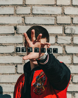 Close-up of human hand against brick wall