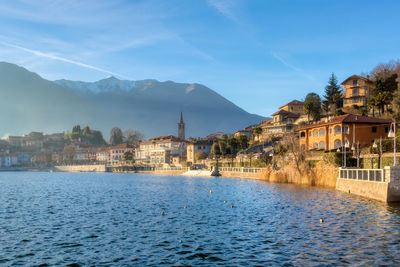 Houses by lake against sky in city