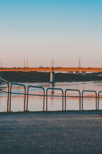 Bridge over sea against clear sky during sunset