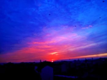 Silhouette city against sky during sunset