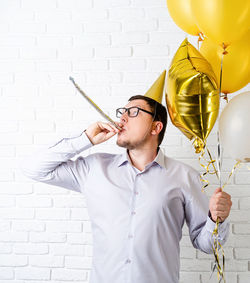 Young man with balloons against wall