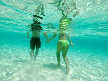 Low section of women swimming in sea