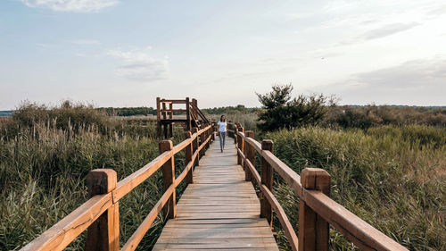 Young woman on wooden pathway in nature park. spring, summer, tourism, travel.