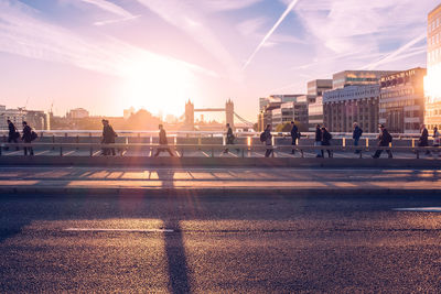 People on street in city against sky during sunset