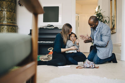 Parents playing with daughter while sitting in living room at home