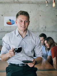 Portrait of a smiling young man holding smart phone