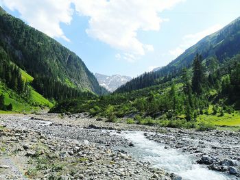 Scenic view of river by mountains against sky