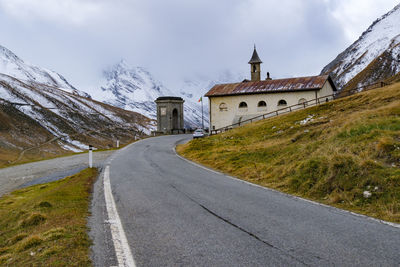 Road leading towards church against sky