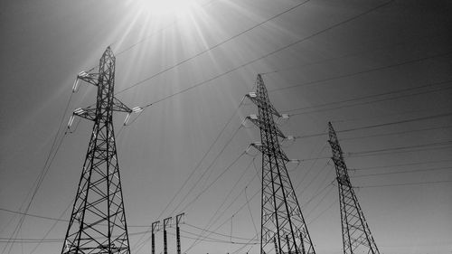 Low angle view of electricity pylons against sky