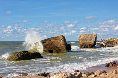 Scenic view of rocks on beach against sky