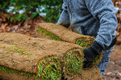 Low section of man stacking turf outdoors