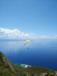 Person paragliding over sea against sky