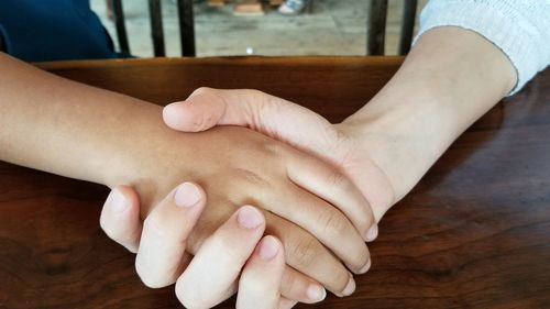 High angle view of couple hands on table