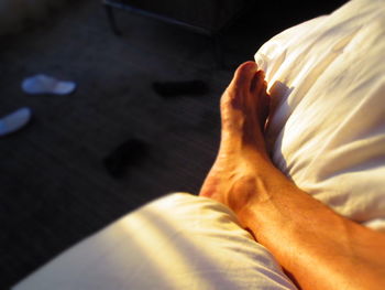 Low section of person resting on bed at morning