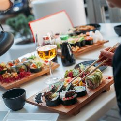 Close-up of hand holding food with chopsticks on table