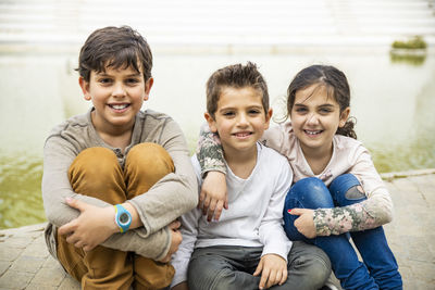 Portrait of happy friends sitting on footpath