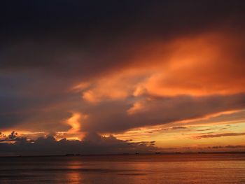 Scenic view of sea against dramatic sky during sunset