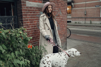 Woman with dog standing against brick wall
