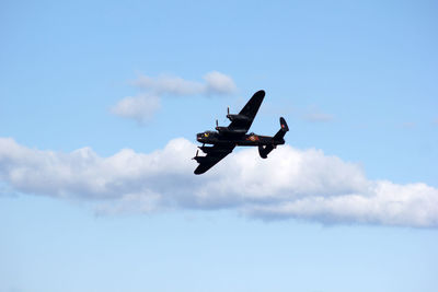 Low angle view of fighter airplane flying against blue sky