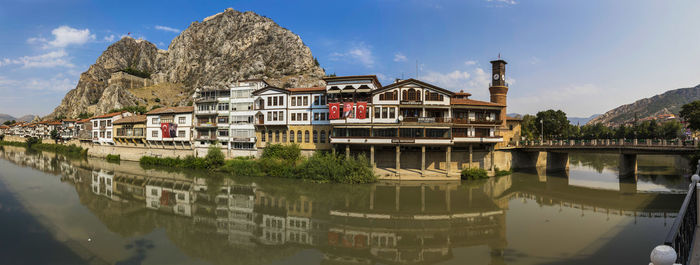 Buildings by river against sky in city