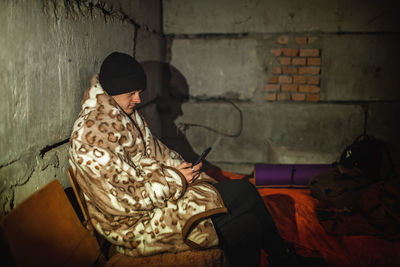 Ukrainian young man sits in bomb shelter and reads latest braking news about russian invaders