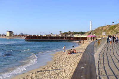 People on beach against clear sky