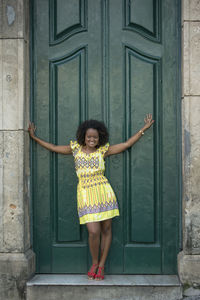 Portrait of young woman standing against door