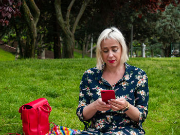 Young woman using mobile phone on field