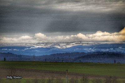 Scenic view of field against cloudy sky