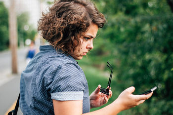 Young woman photographing through phone on street