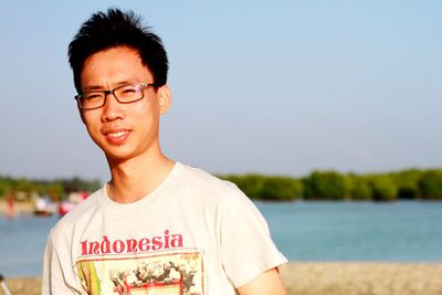 Portrait of smiling man standing against lake