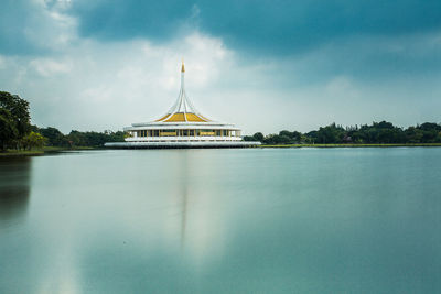 View of church in lake against cloudy sky