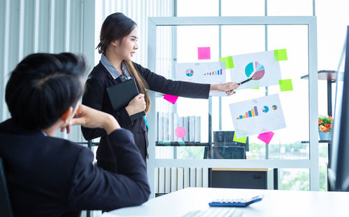 Side view of young woman using mobile phone in office