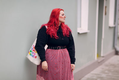 Young woman standing against wall