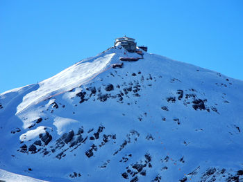 Low angle view of snowcapped mountain against clear blue sky